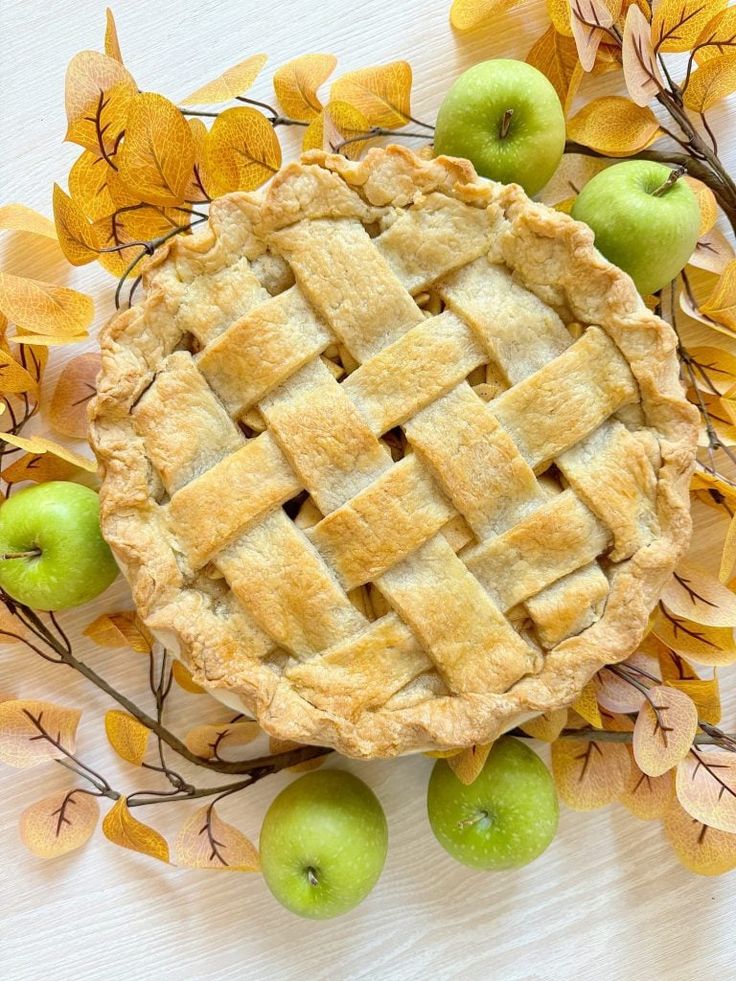 an apple pie surrounded by autumn leaves and apples