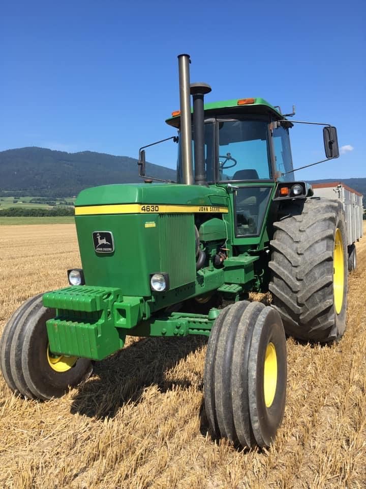 a green tractor in a field with mountains in the background