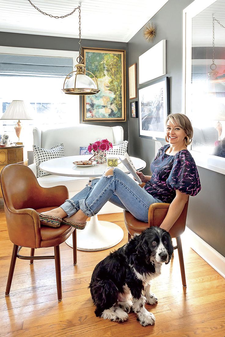 a woman sitting in a chair next to a dog on top of a hard wood floor