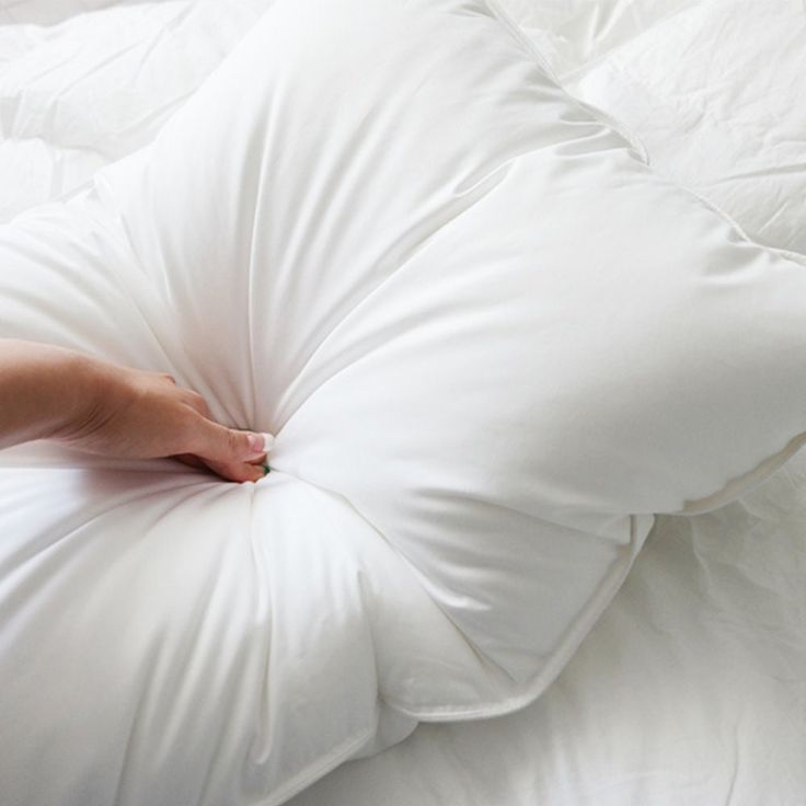 a person's hand on the back of a white pillow