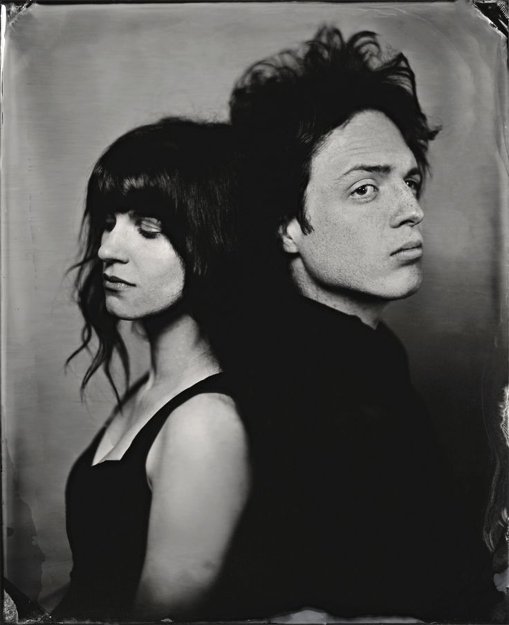 a man and woman are posing for a black and white photo with hair blowing in the wind