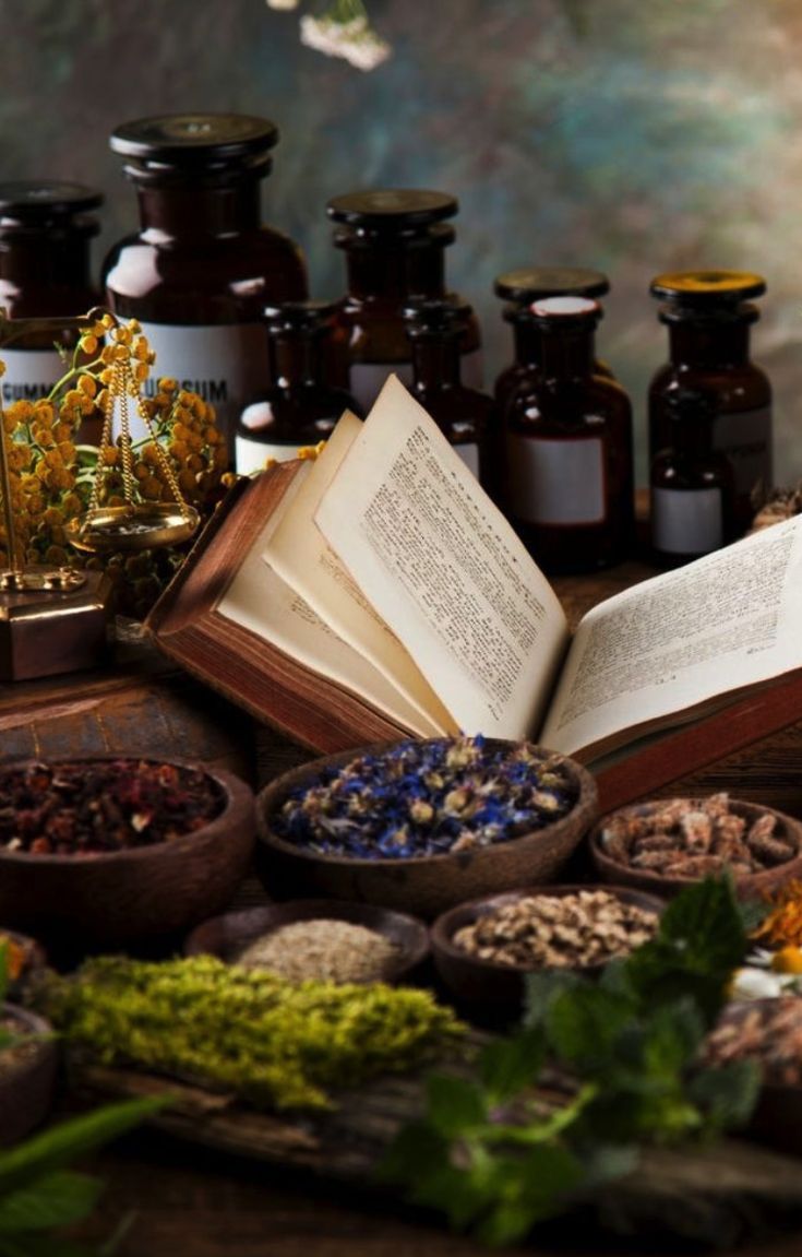 an open book sitting on top of a wooden table filled with herbs and medicine bottles