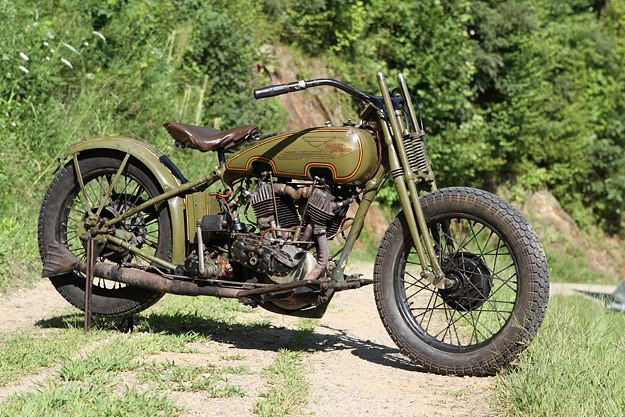 an old motorcycle parked on the side of a dirt road