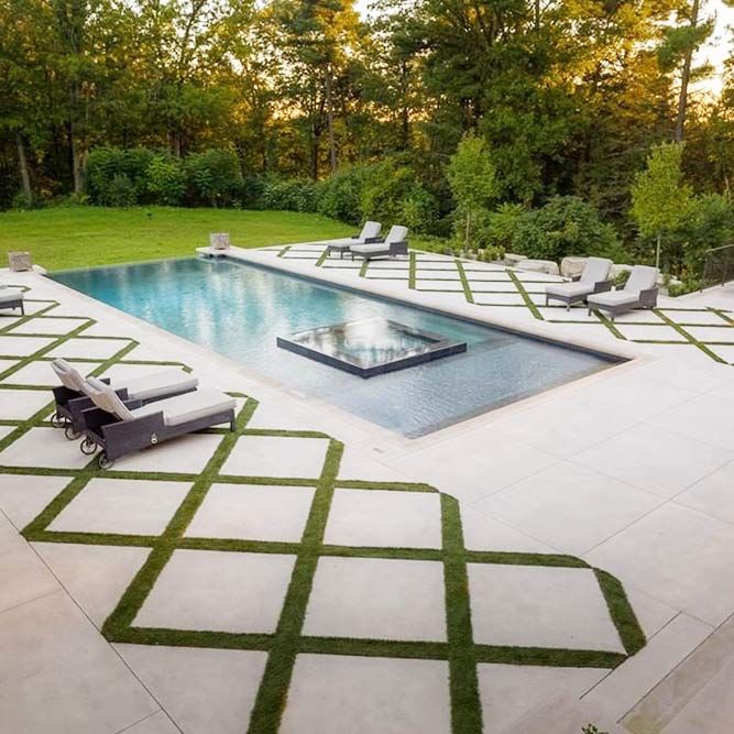 an outdoor swimming pool surrounded by grass and lawn furniture with lounge chairs on the side