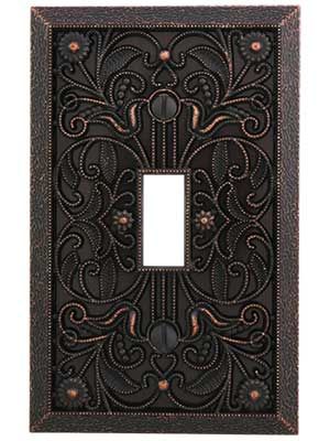 an ornate metal switch plate with a decorative design on the front and back cover,