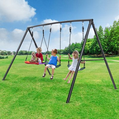 three children playing on swings in the grass