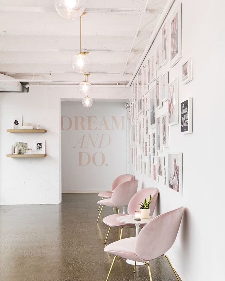 pink chairs are lined up against the wall in front of pictures on the walls and shelves