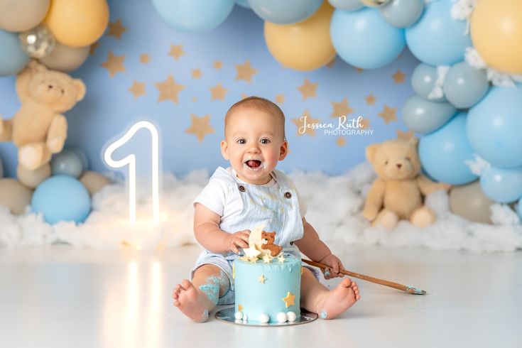 a baby sitting in front of a blue cake with gold stars on it's face