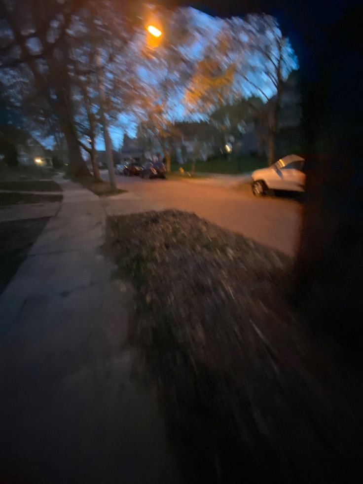 a blurry photo of a street at night with cars parked on the side of the road