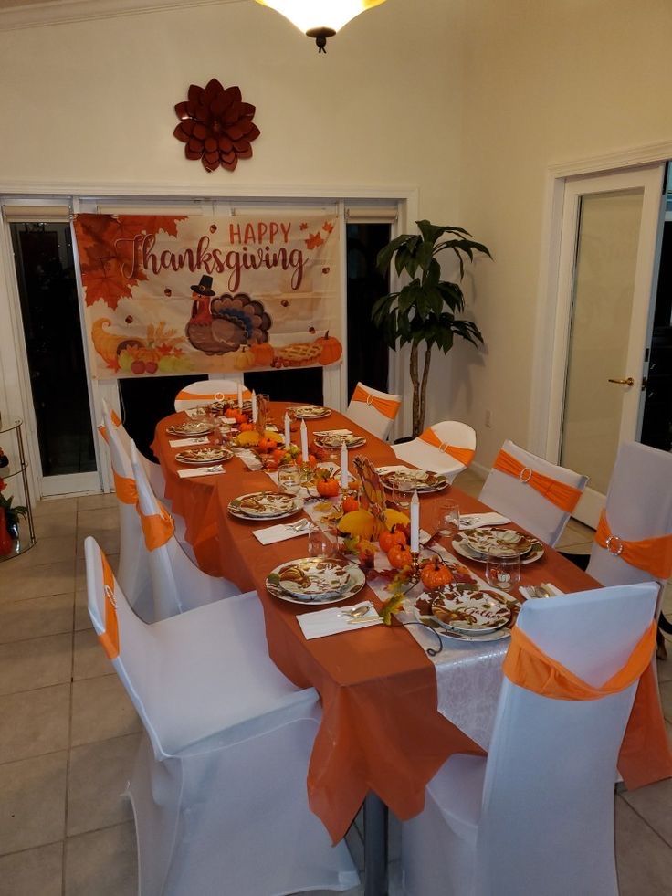 a table set for thanksgiving dinner with orange and white linens on the chair covers