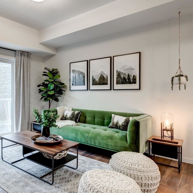 a living room with green couches and pictures on the wall above them in front of a window