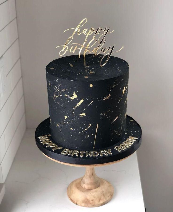 a black and gold birthday cake on a pedestal