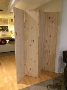 a room divider made out of plywood planks in a living area with hardwood floors