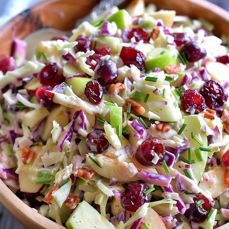 a salad in a wooden bowl with cranberries and apples