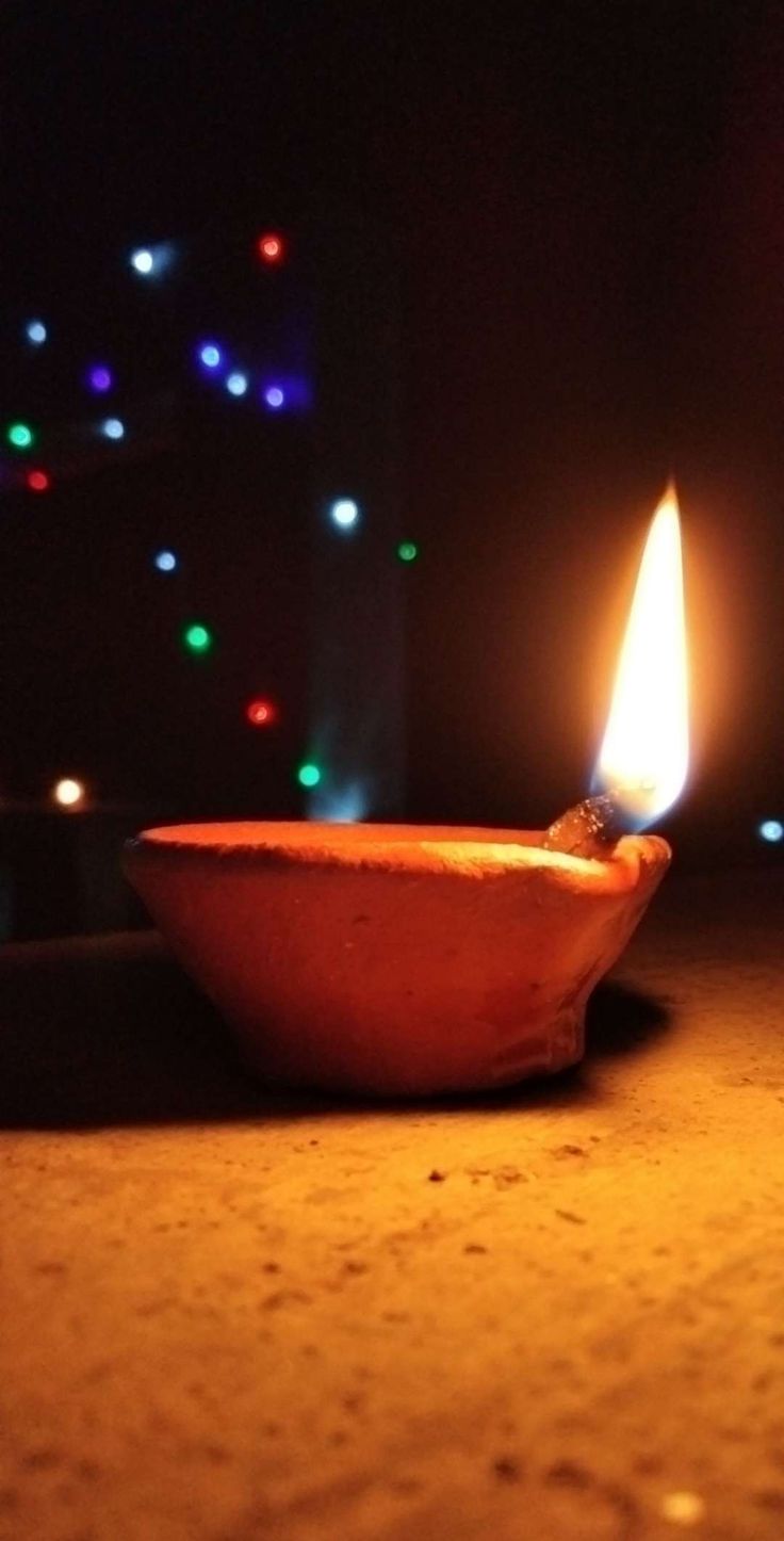 a lit candle sitting on top of a table next to a bowl filled with food