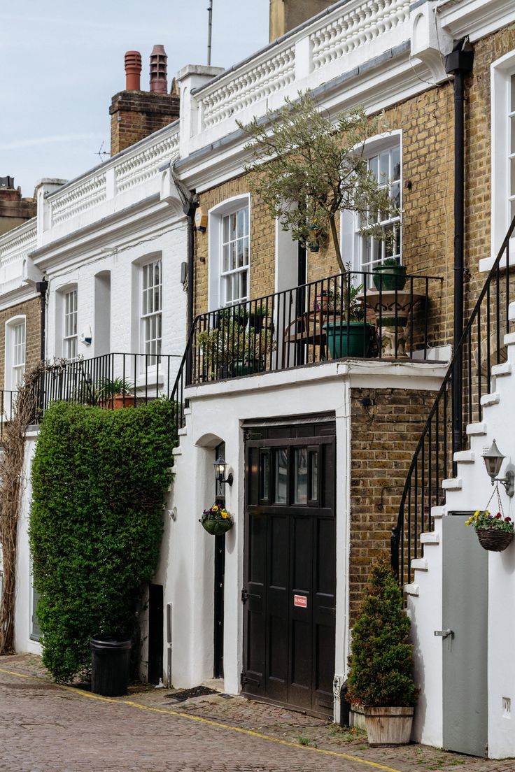 a row of houses with plants growing on the balconies and stairs leading up to them