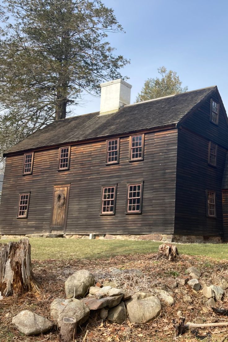 an old wooden house with many windows and rocks on the ground in front of it