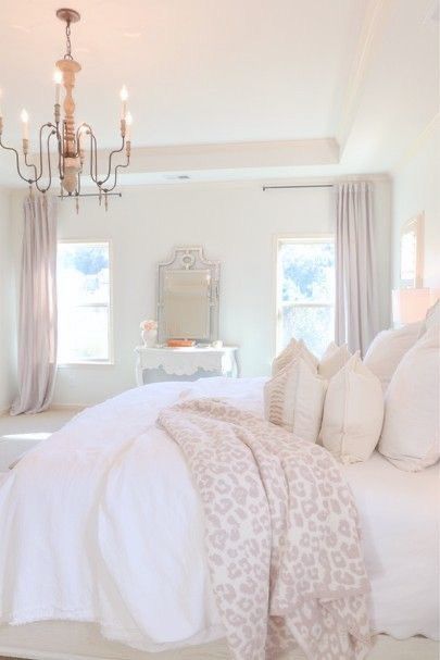 a bedroom with a bed, chandelier and two windows