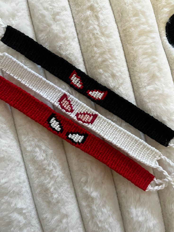 two white and black bracelets laying on top of a bed next to each other