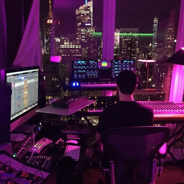 a man sitting at a desk in front of a computer monitor and sound mixing equipment