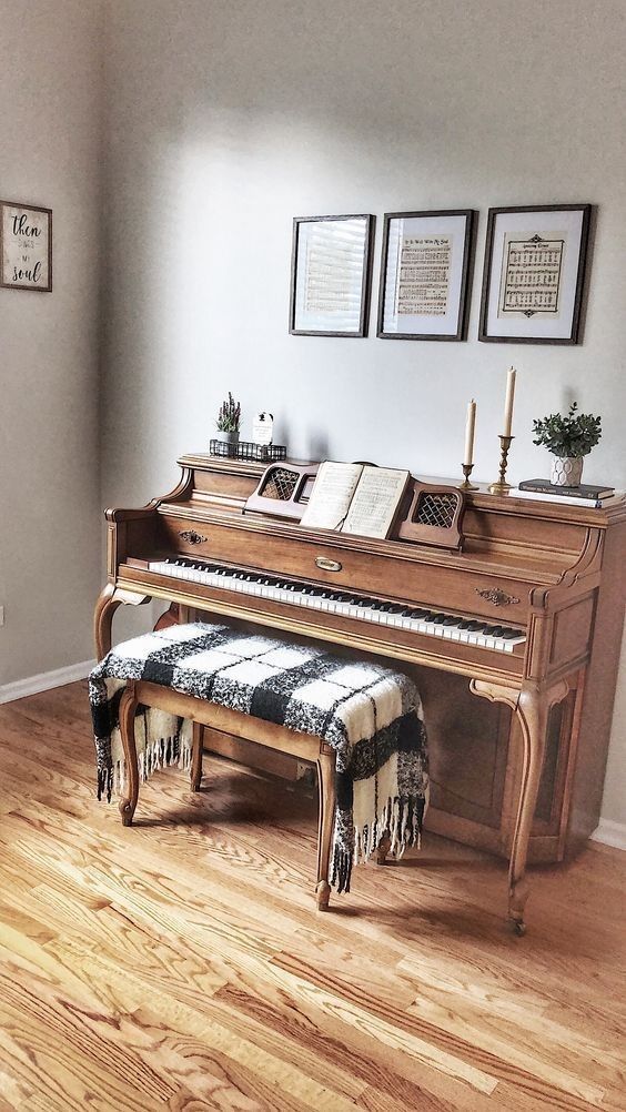 a piano sitting on top of a hard wood floor next to a wall with pictures above it