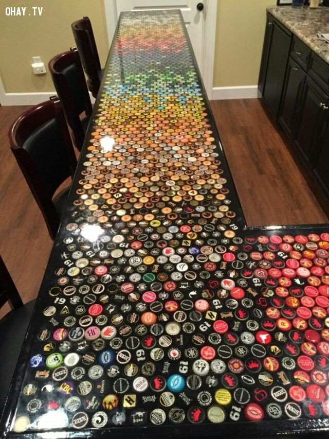 a long table covered in lots of different colored bottle caps on top of a wooden floor