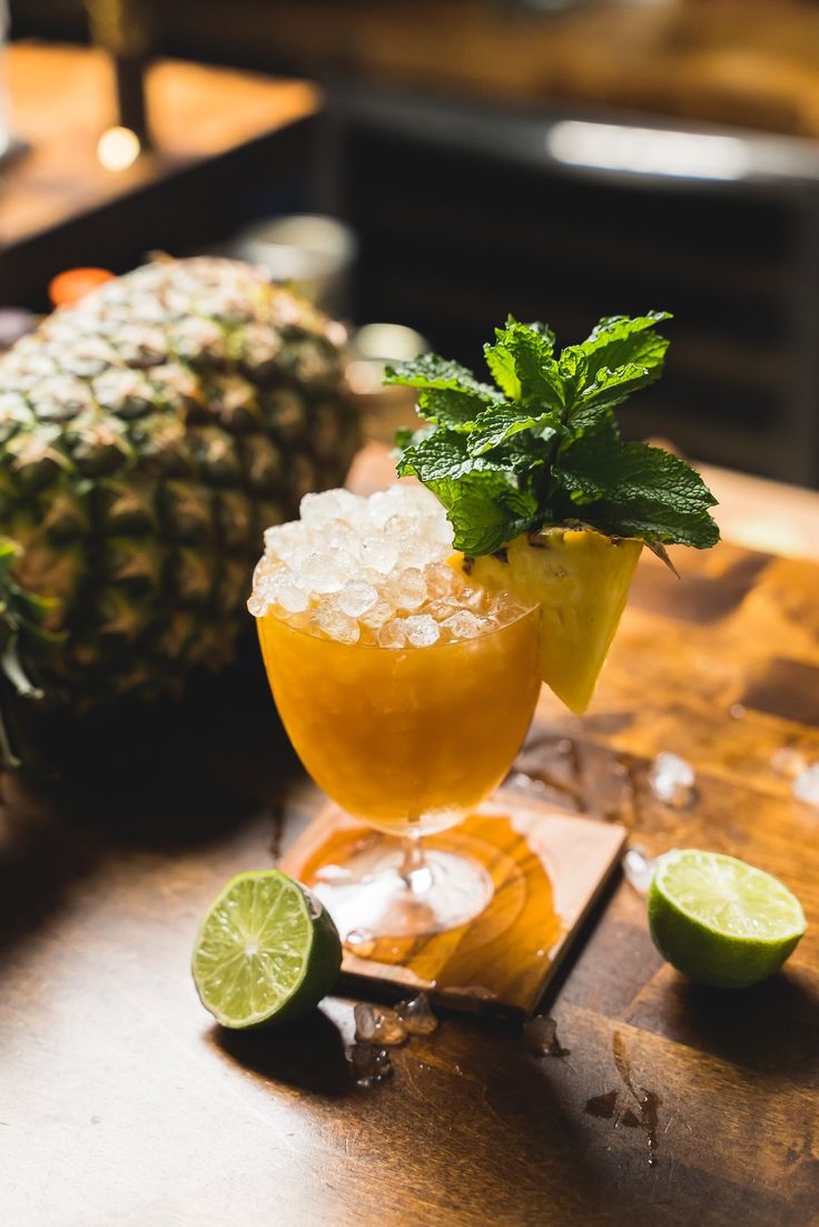 a pineapple margarita sits on a wooden table