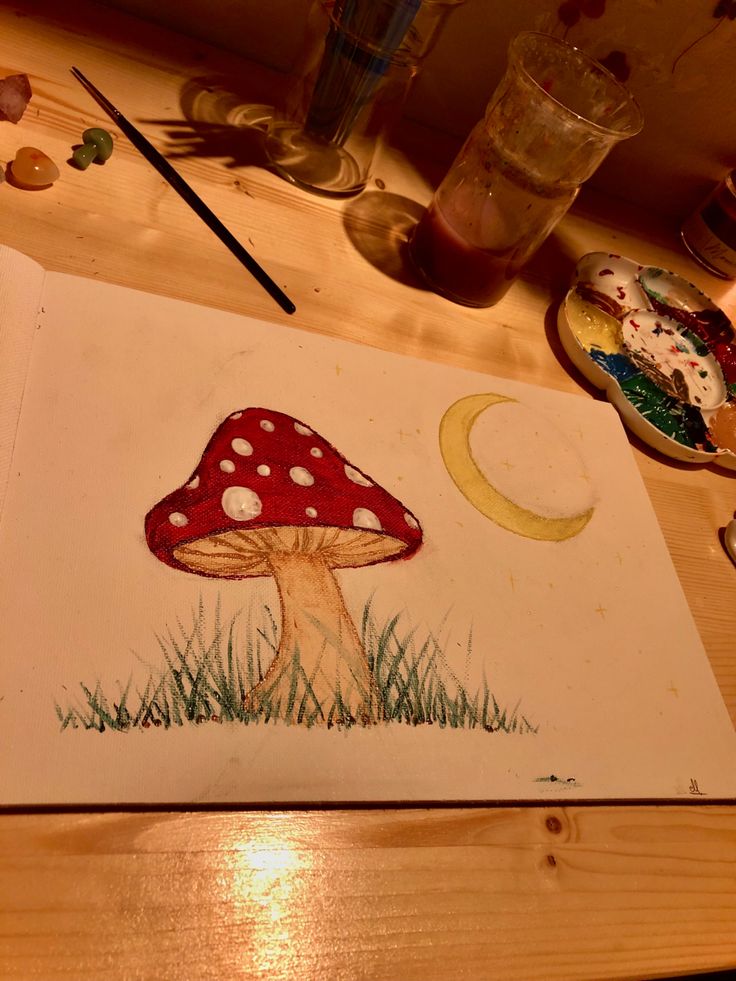 a drawing of a mushroom sitting on top of a wooden table next to a paintbrush