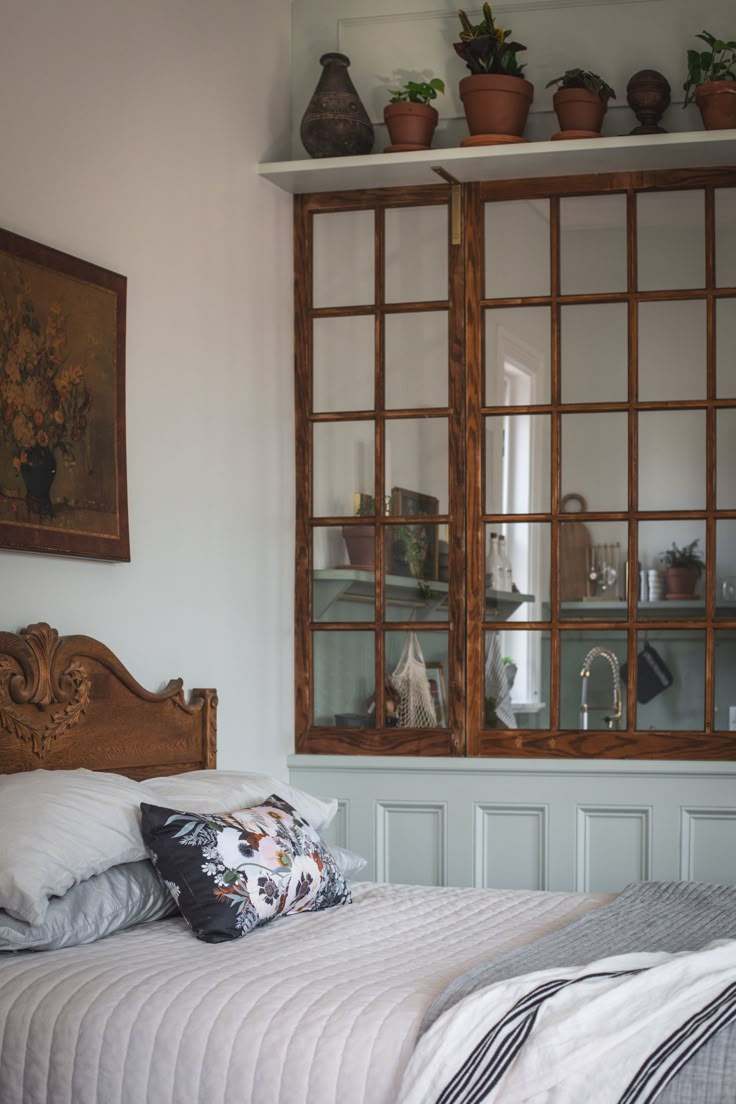 a bed sitting in a bedroom next to a window with potted plants on top of it