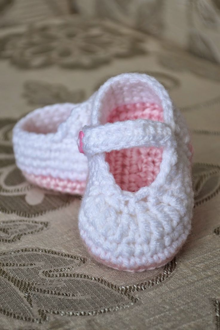 a pair of crocheted baby shoes sitting on top of a bed