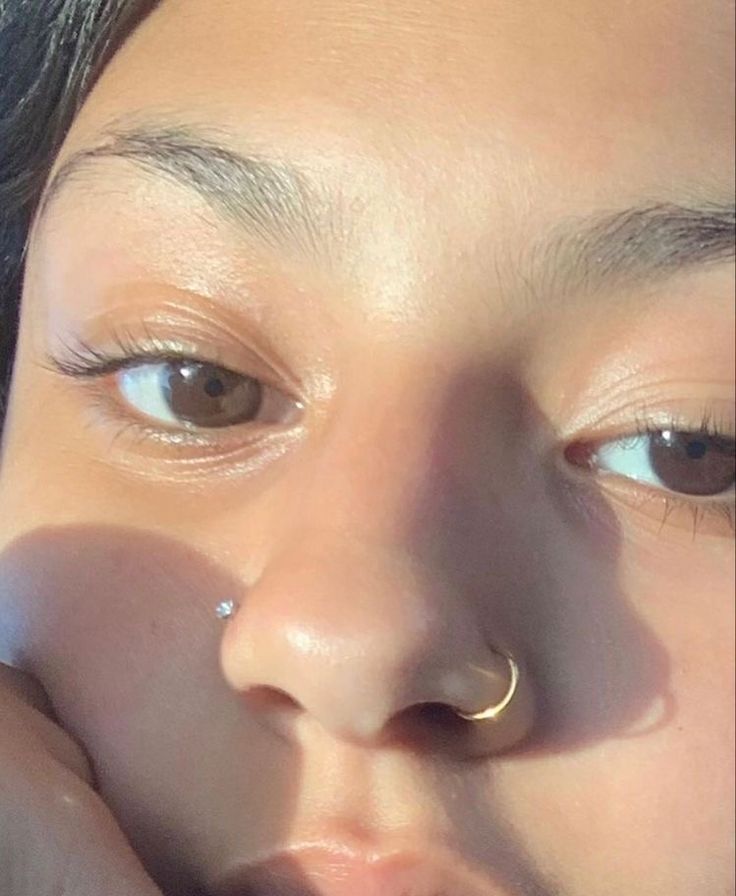 a close up of a person with a nose ring on their nose and one eye open