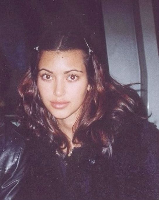 a woman with long hair wearing a black jacket and looking at the camera while sitting in a car