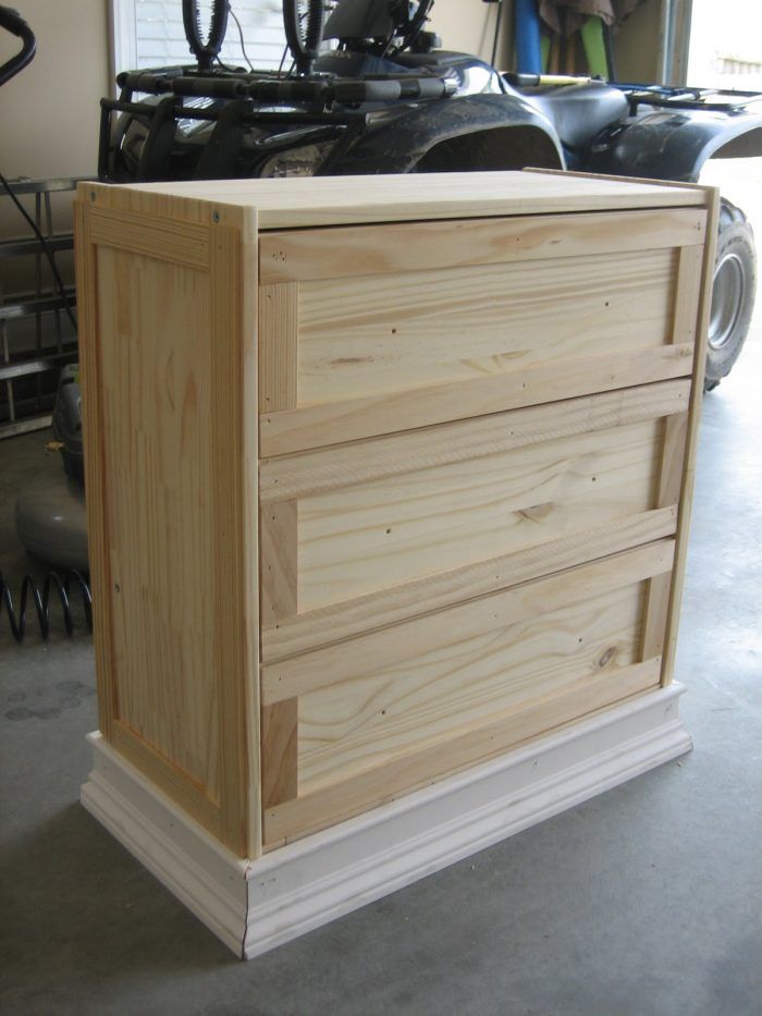 a wooden dresser sitting inside of a garage next to a motorcycle parked in the background