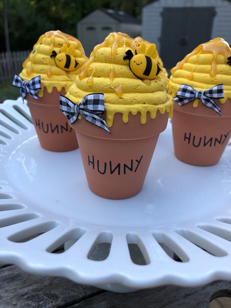 three cupcakes with yellow frosting and bees on them sitting on a white plate