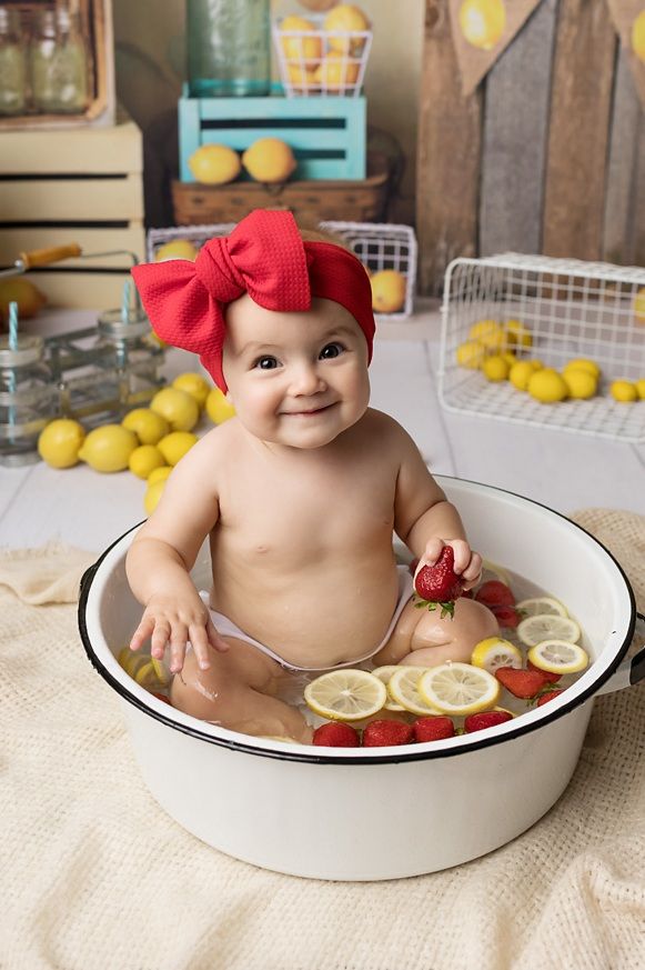 a baby sitting in a tub with lemons and strawberries