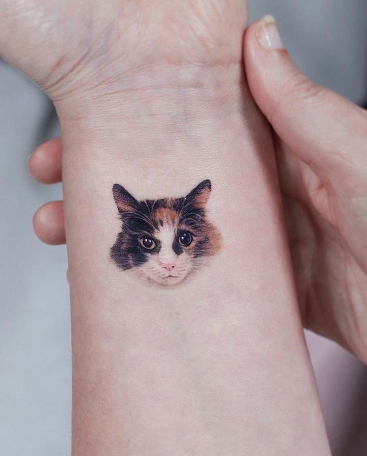 a cat's face on the wrist is shown in this tattoo design by an artist