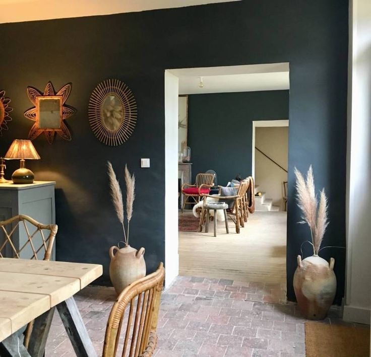 a dining room table with chairs and vases on the wall in front of it