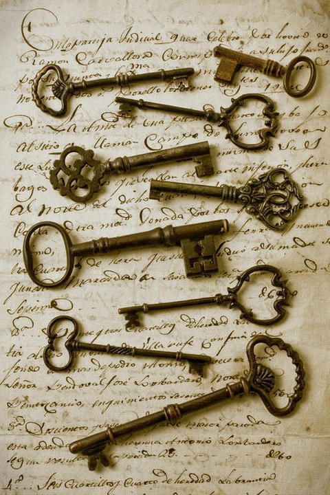 old keys are arranged on top of an antique manuscript