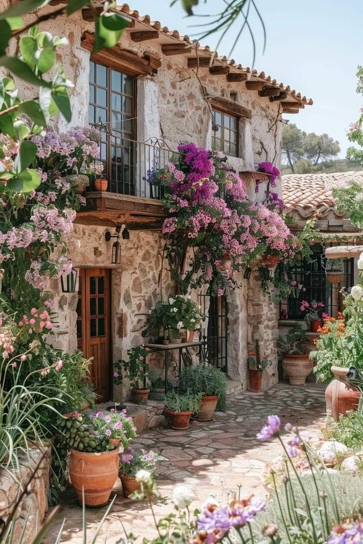 an old stone house with potted plants and flowers