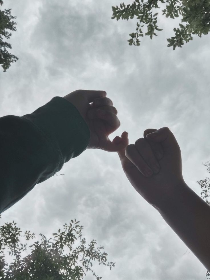 two people reaching up into the sky with their hands in each other's arms