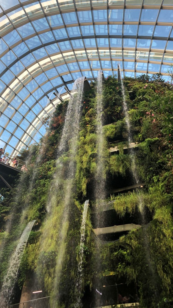 an indoor waterfall in the middle of a building with lots of greenery on it