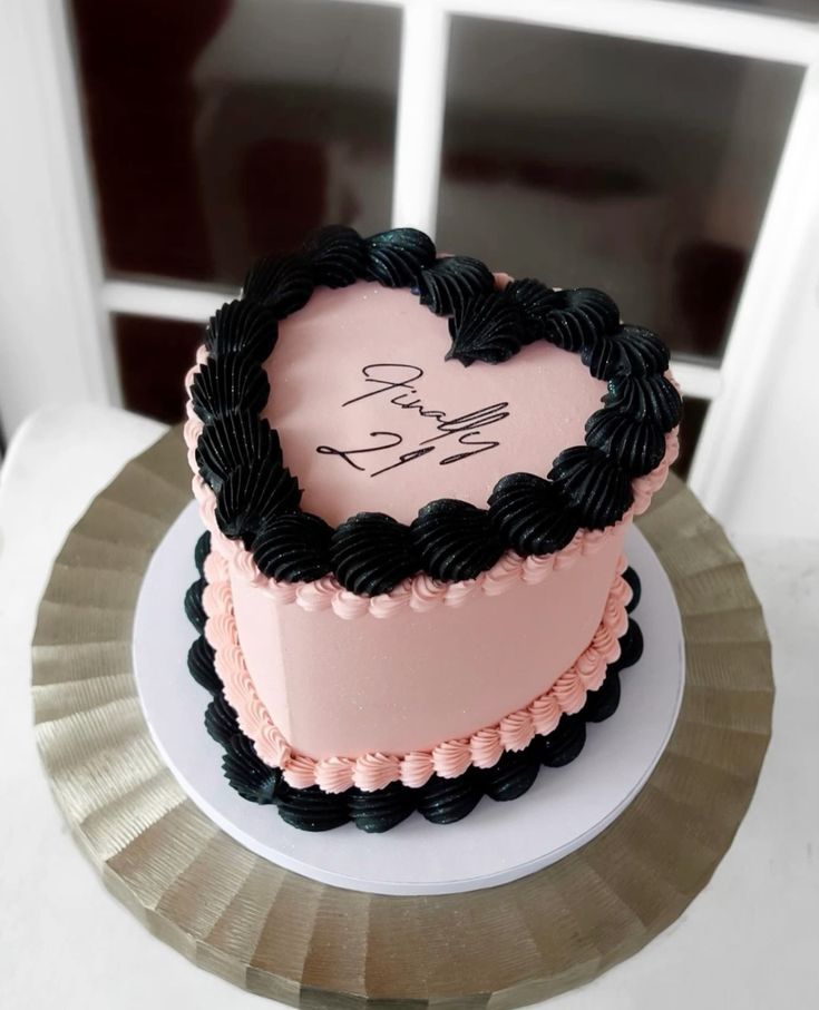 a pink and black heart shaped cake sitting on top of a table