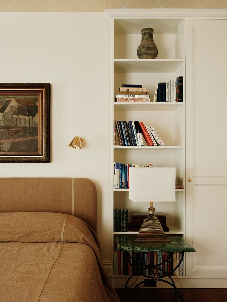 a bed sitting next to a book shelf filled with books