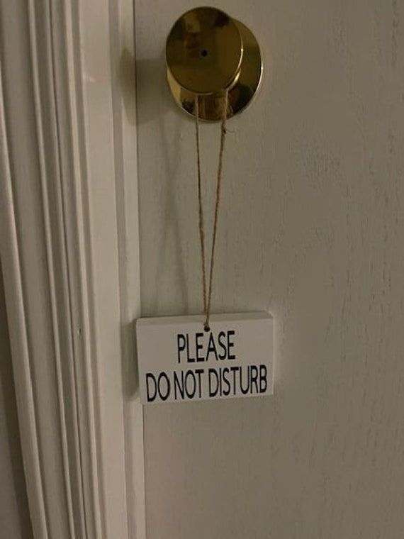 a sign hanging from the side of a door that says please don't disturb