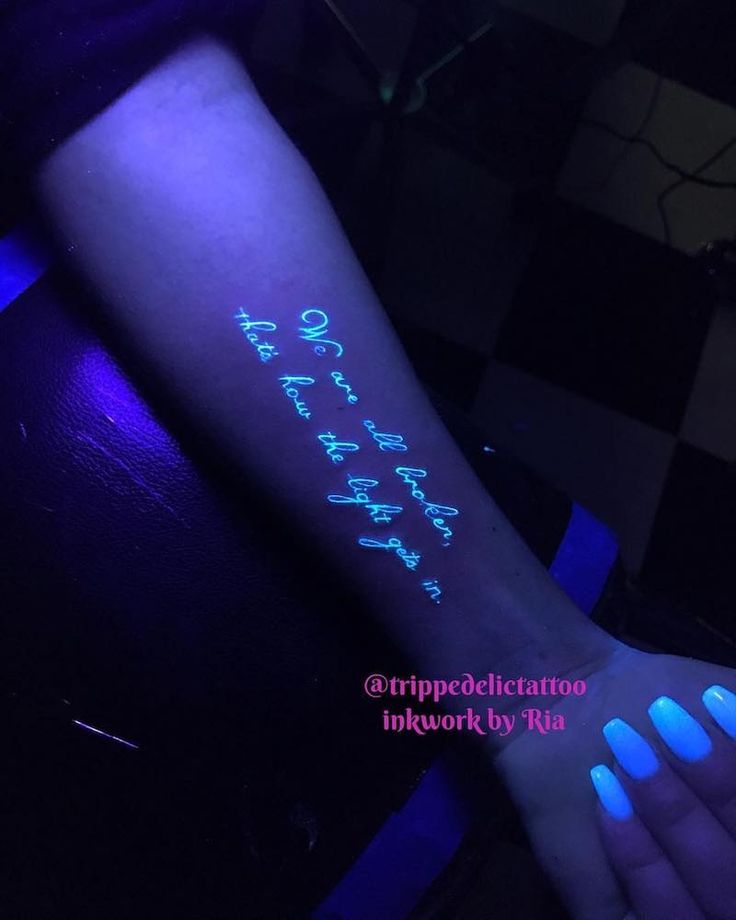 a person's arm with glow in the dark writing on it and blue nail polish