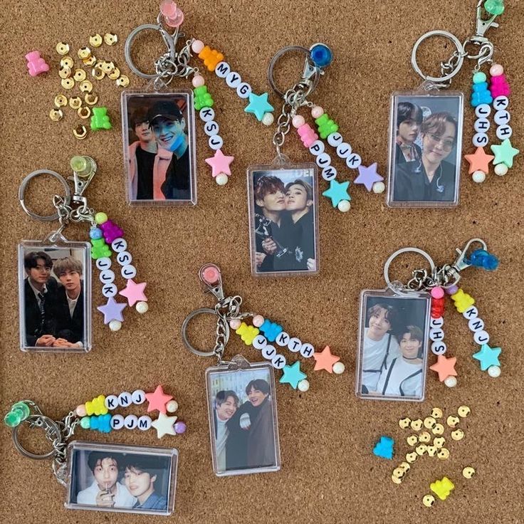 several different key chains with pictures attached to them on a corkboard surface, one has an image of two people and the other is colored stars