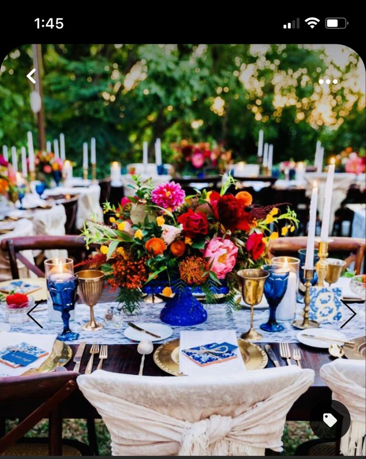 a table set up with blue and white plates, silverware, and colorful flowers