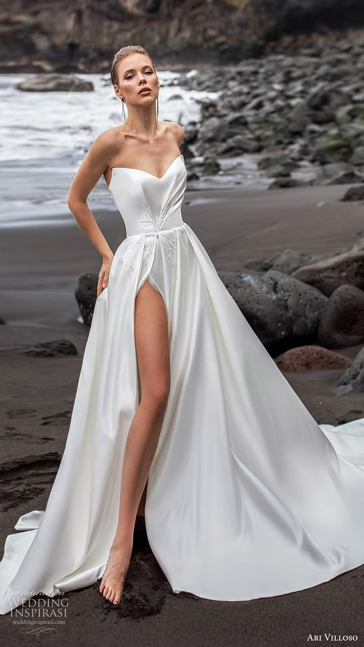 a woman standing on the beach wearing a white dress with high slit and thigh high split