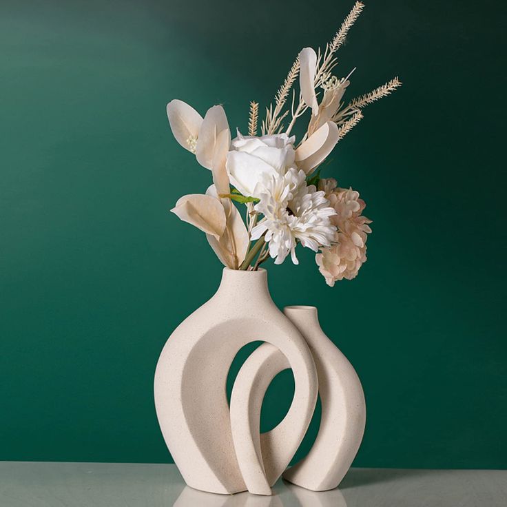 a white vase with flowers in it on a table