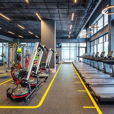 an empty gym with rows of treadmills and exercise machines in the foreground